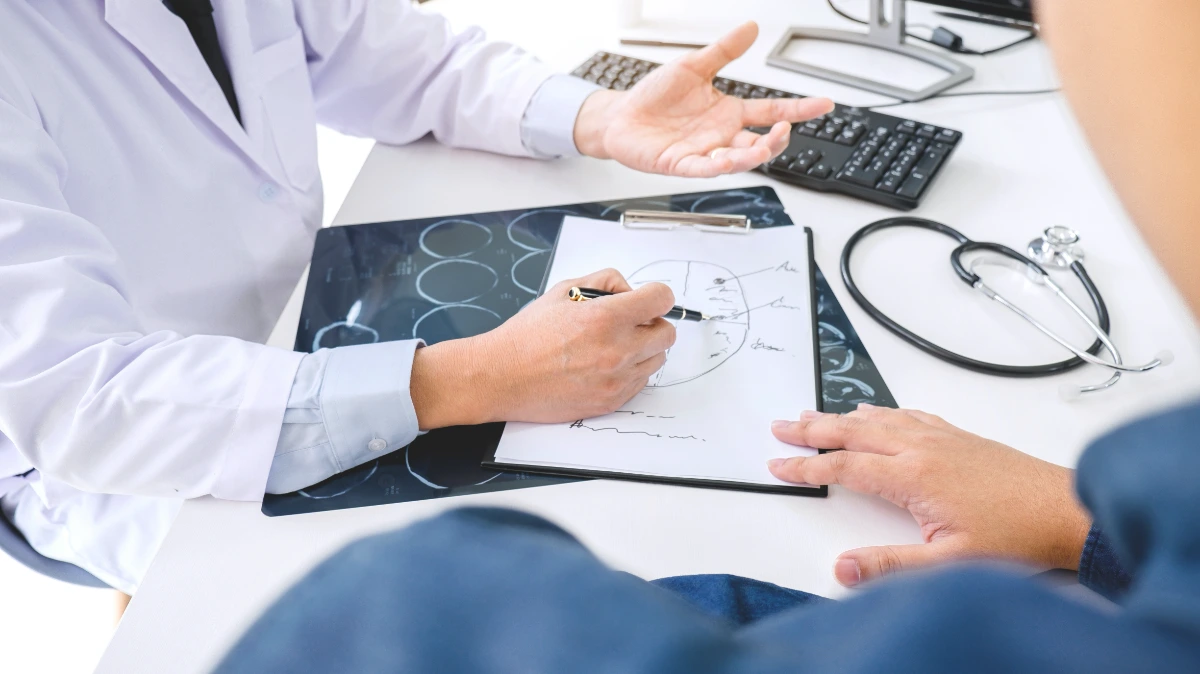Médico neurofisiólogo explicando a un paciente sobre un diagrama del cerebro si es candidato al tratamiento con EMTr.